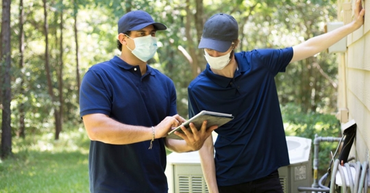 Workers examine a building/home's exterior walls.